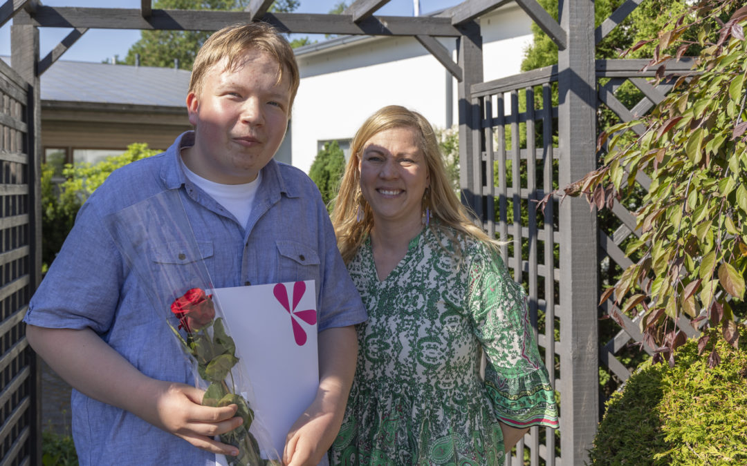 Tuva-opiskelija Juho todistus ja ruusu kädessään ja opo Hanna Raiskio.