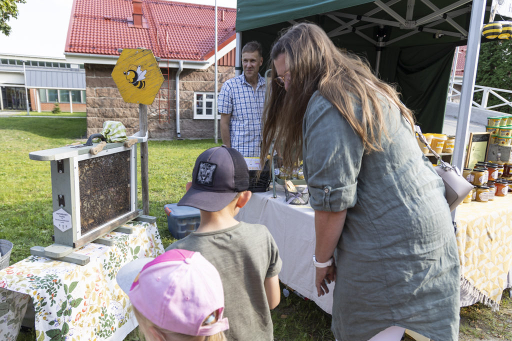 Äiti ja lapset katselevat mehiläiskennoa Lintulan Hunajan osastolla.