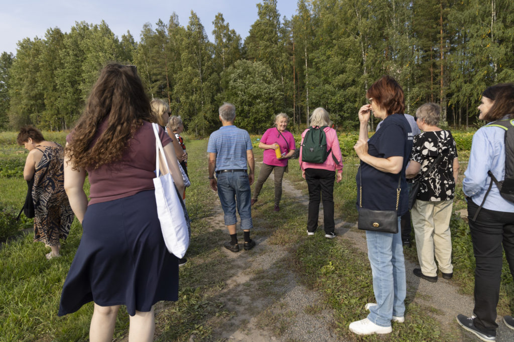 Ryhmä ihmisiä tutustumassa Kiipulan luomuavomaahan puutarhurin johdolla.