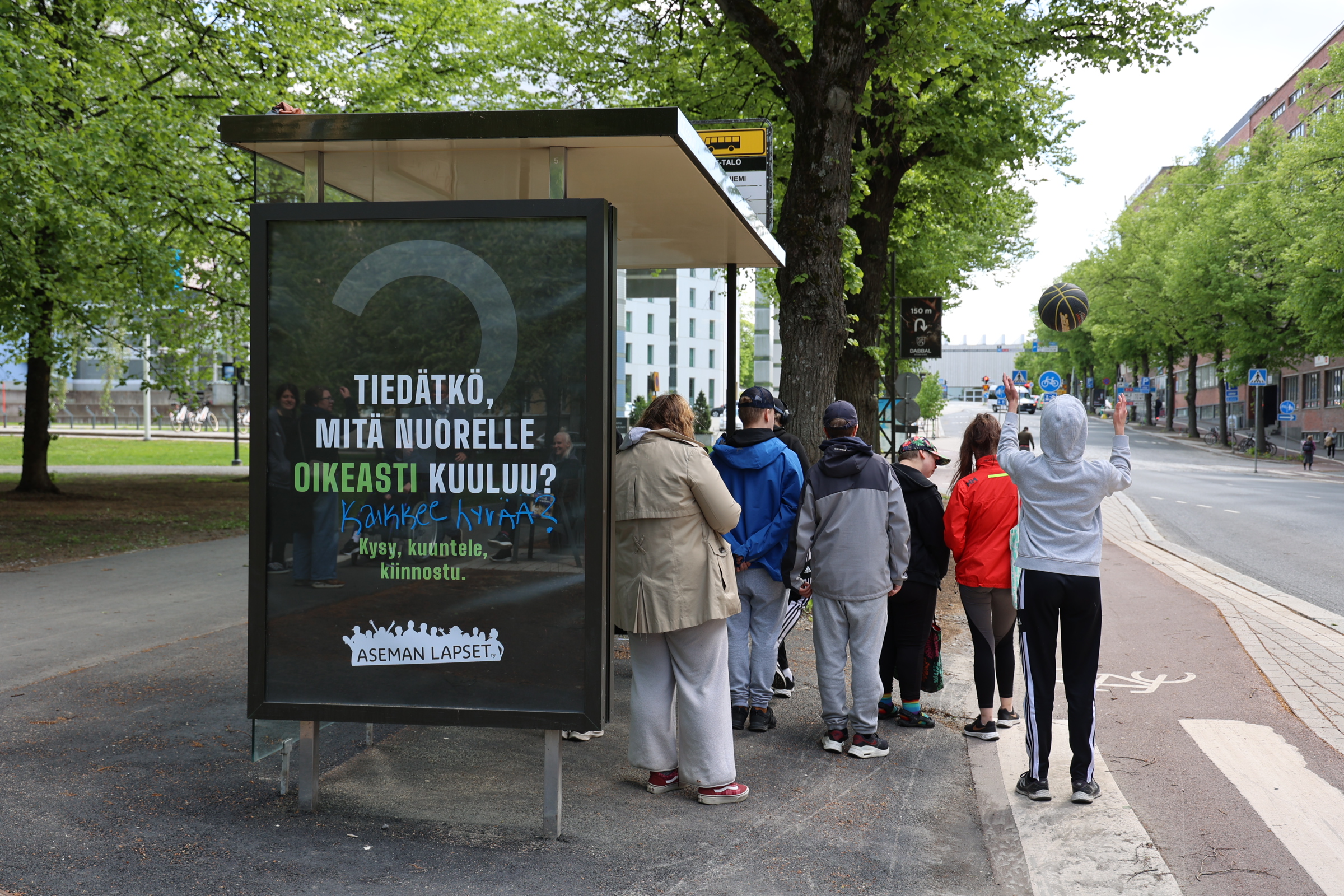 Opiskelijat bussipysäkillä odottamassa bussia.